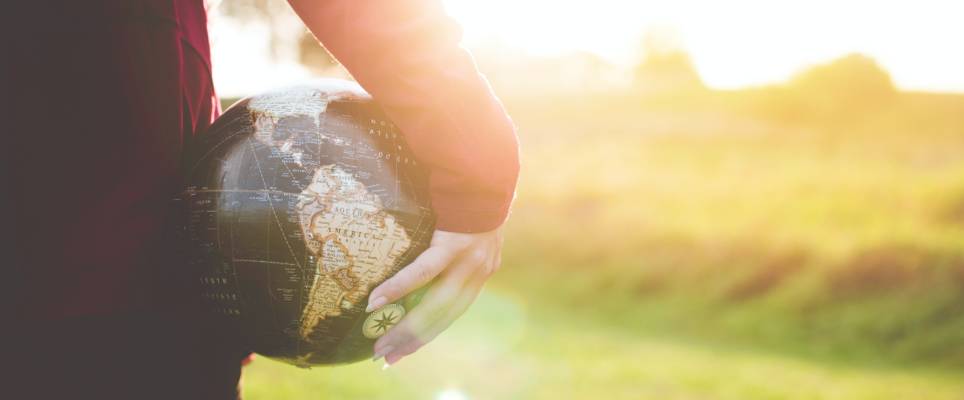 Person holding a globe. Sunlight, field.